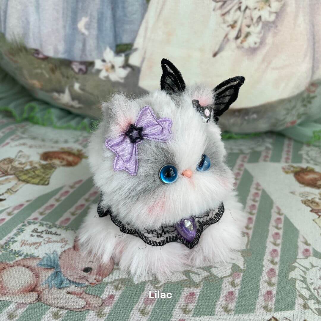 Hand-sculpted plush kitten with purple bow and black lace, inspired by cosplay and magical girls. Part of the Cosplay Kitten Collection.