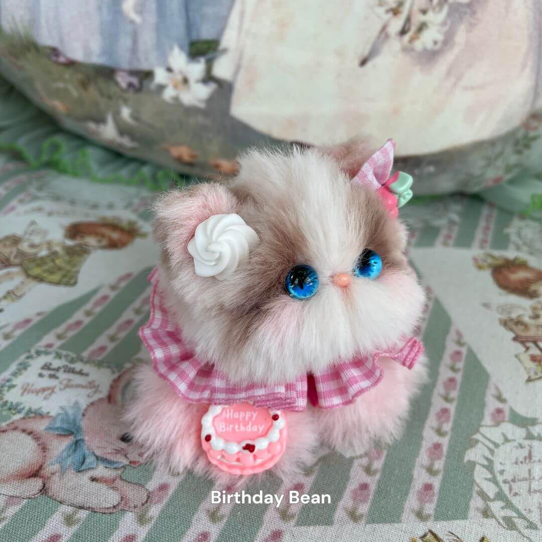 Handcrafted Cosplay Kitten plush toy with pink dress, blue eyes, and birthday cake decoration from the Cosplay Kitten Collection.
