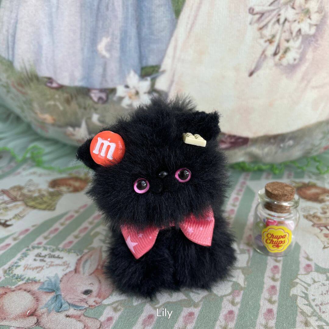 Handmade black kitten figurine with pink eyes, candy-inspired bow, and whimsical accessories, part of the Black Kitten Collection.