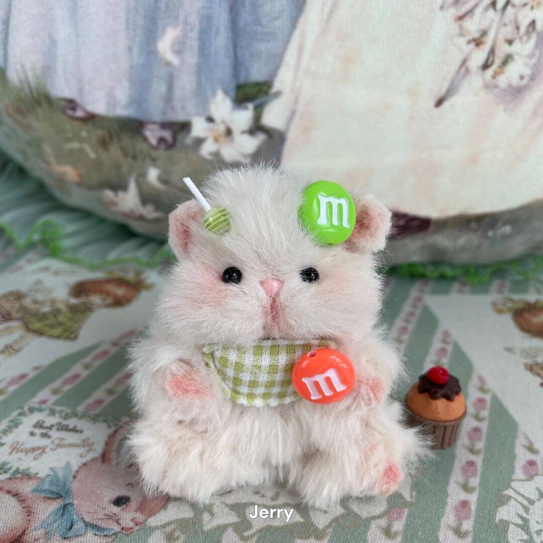 Handmade fluffy white hamster with green and orange candy decorations, part of the Adorable Hamsters Collection, on a patterned background.