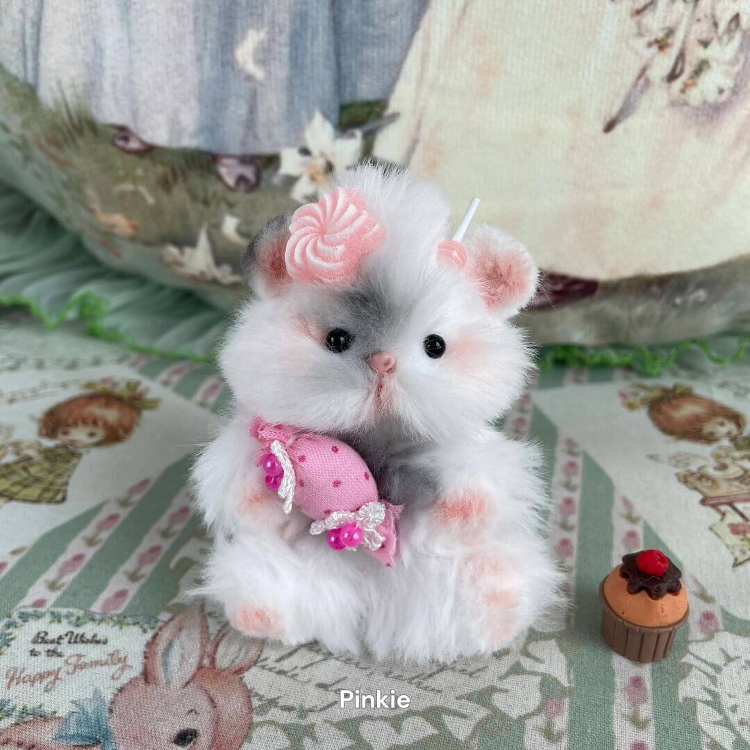 Handmade fluffy hamster with faux fur, holding pink candy, adorned with pastel bows, ideal for animal lovers and decor enthusiasts.