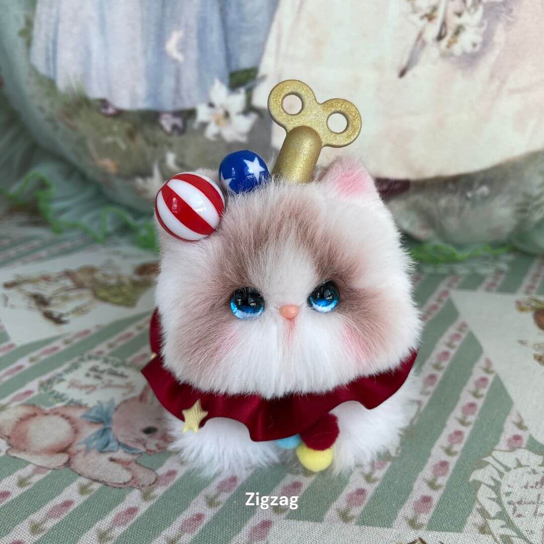 Plush kitten toy with clockwork key, wearing red ruffled dress and colorful accessories, part of the Cosplay Kitten Collection.