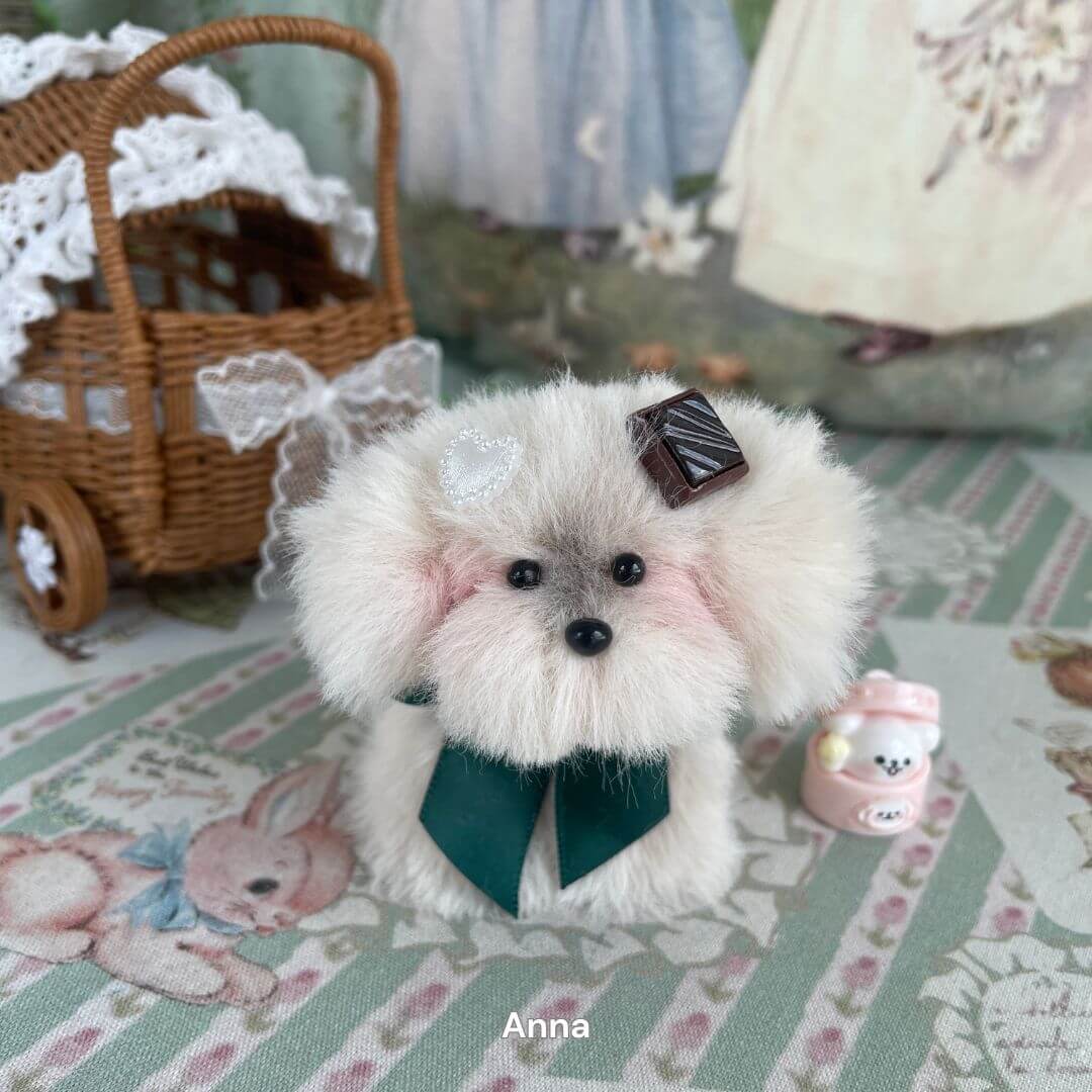 Handmade faux fur puppy plush with ribbon from Adorable Puppy Collection, displayed with decorative accessories in cozy setting.