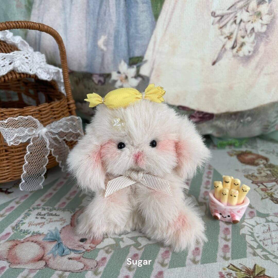 Adorable handmade plush bunny with pink cheeks, yellow bow, and wicker basket, part of the Bunny Collection.