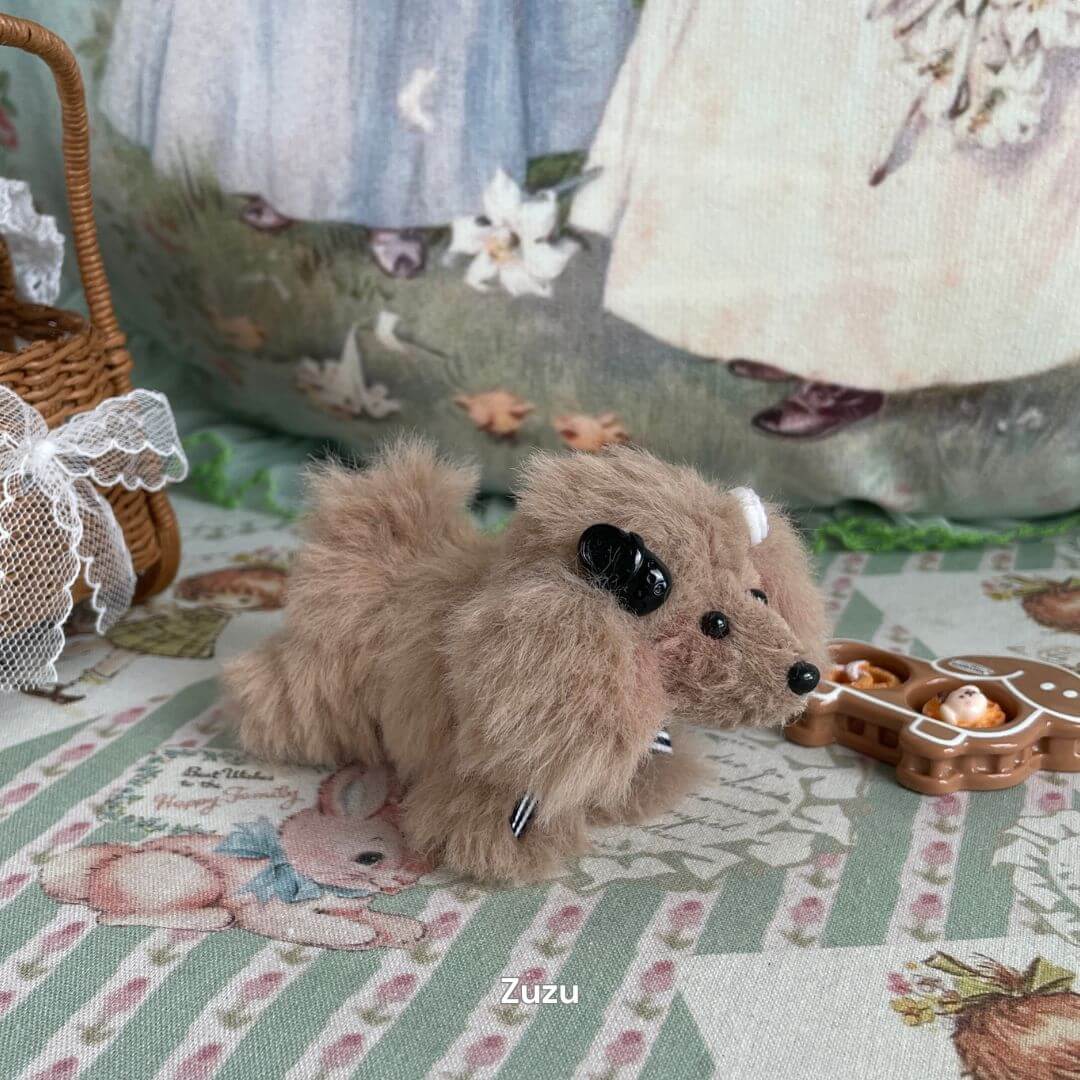 Handmade plush puppy toy 'Zuzu' with soft fur on a floral-pattern table, part of the Adorable Puppy Collection.
