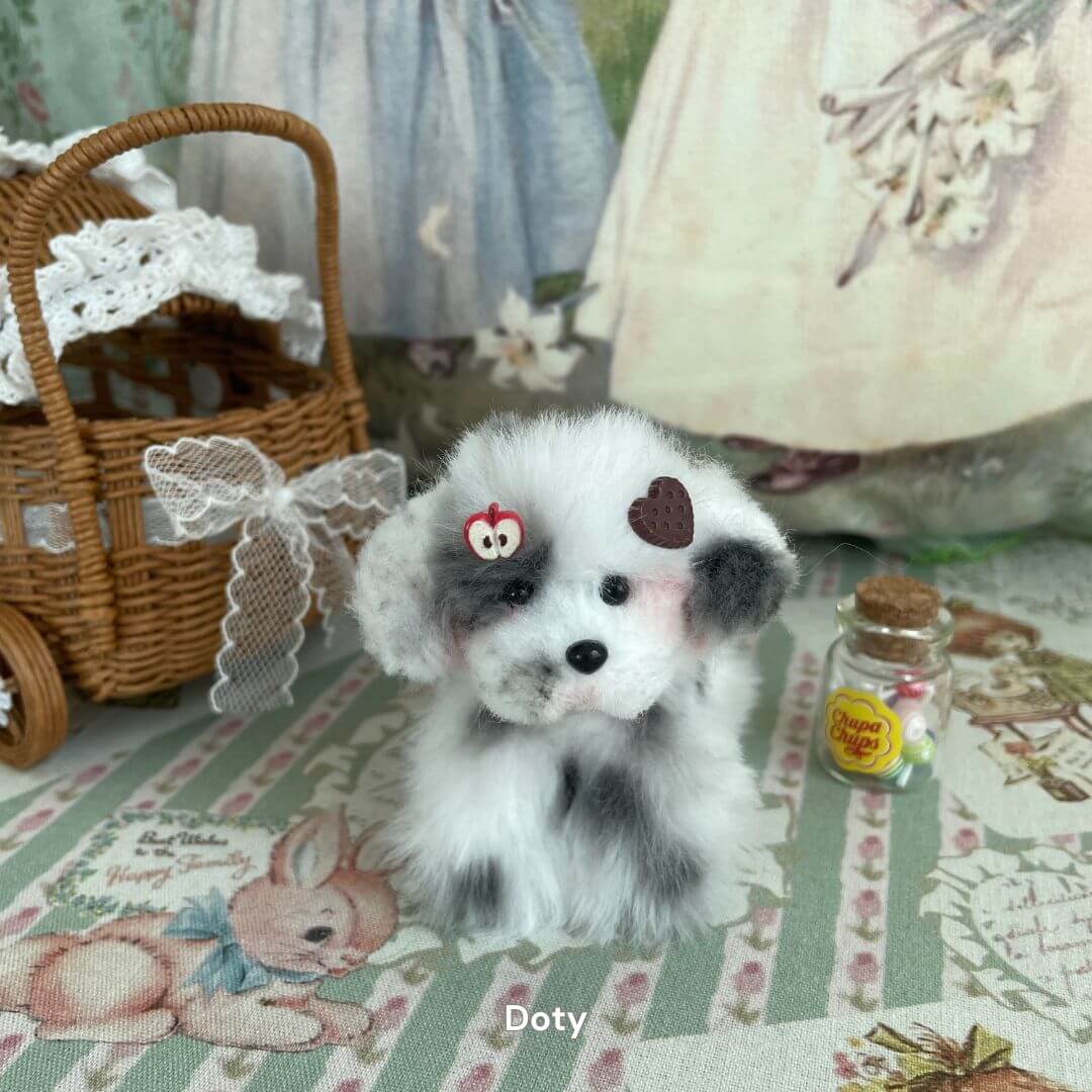 Hand-sculpted plush puppy with heart and apple accessories, part of the Adorable Puppy Collection, near small wicker basket.