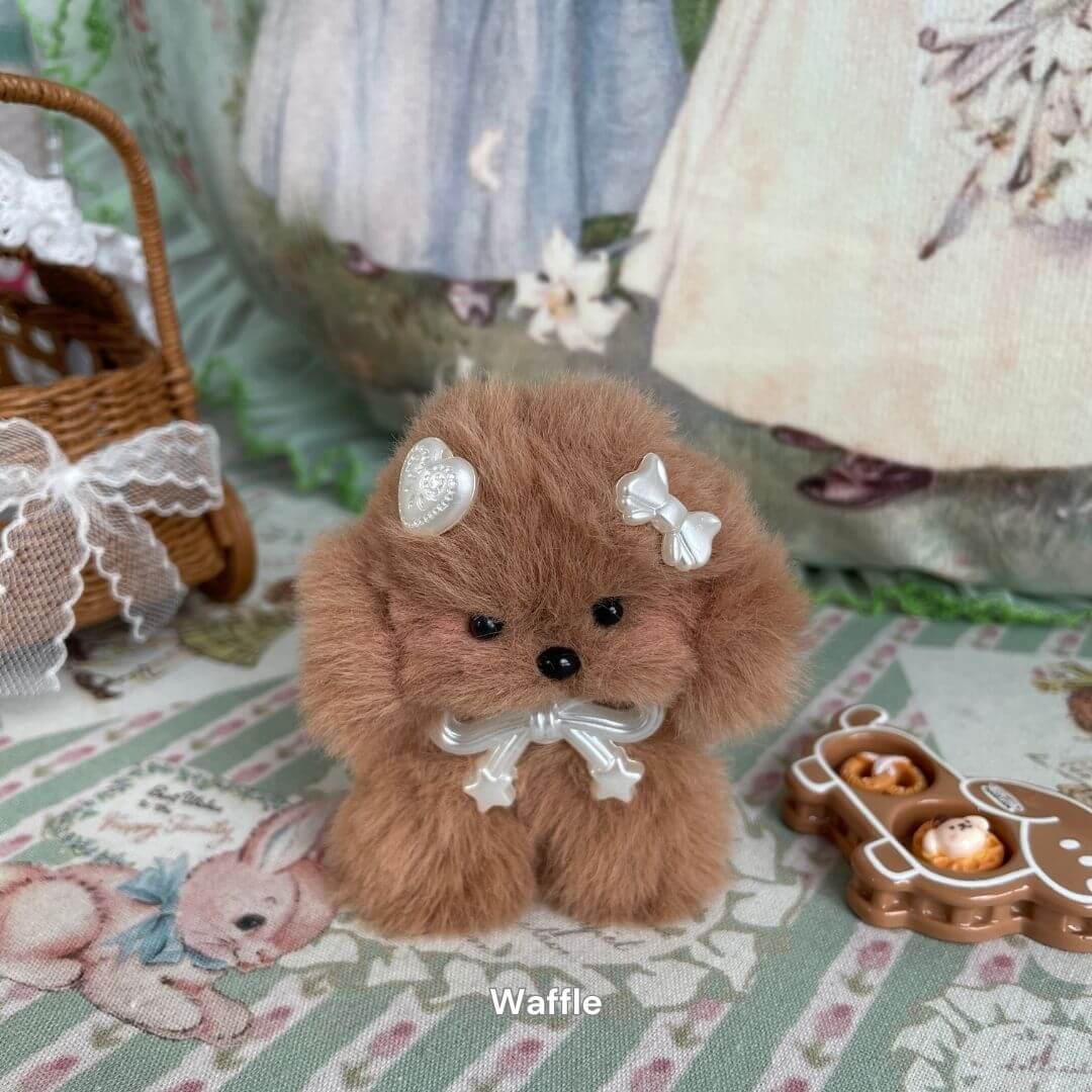 Handmade plush puppy toy named Waffle with faux fur and decorative bow on a patterned background, part of the Adorable Puppy Collection.