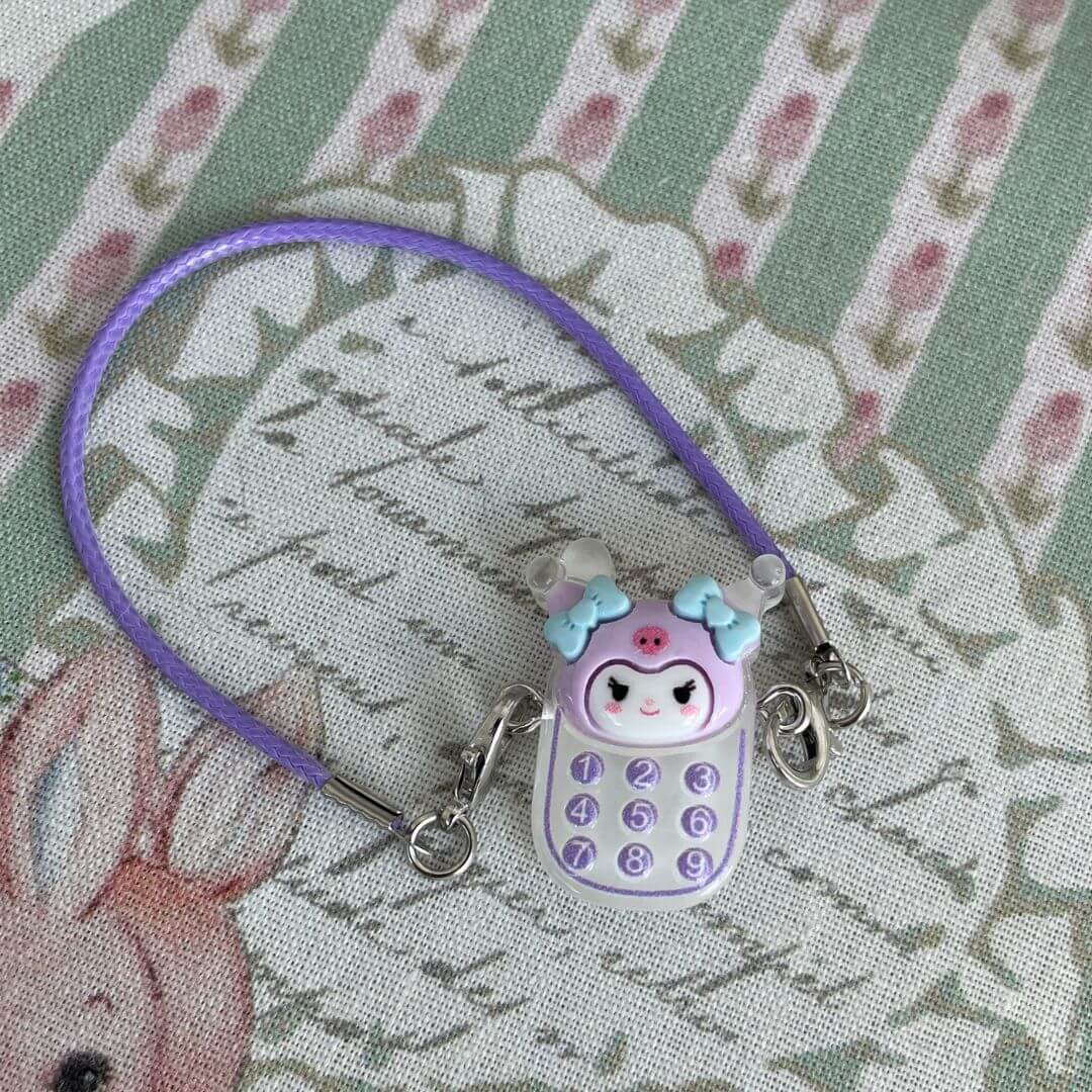 Sanrio character phone charm with purple strap and dial pad, perfect accessory for plush toys or as a cute gift.