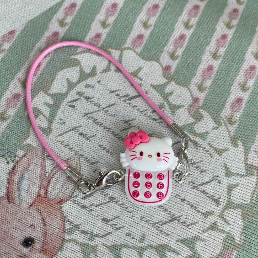 Sanrio character charm with pink strap and dial pad, featuring a cute character face, perfect for accessories or gifts.
