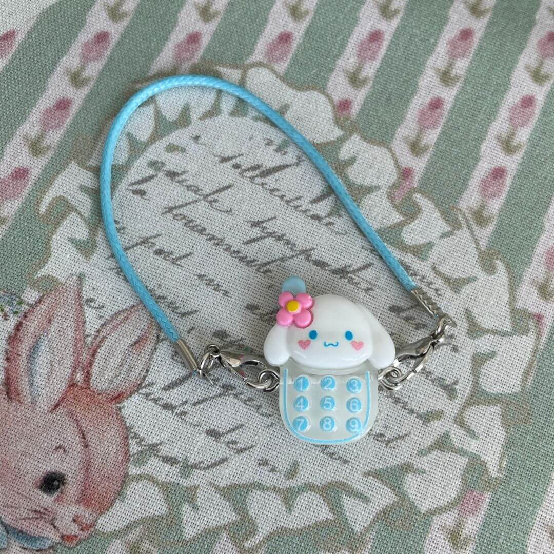 Charmie Dial with Sanrio character face, floral decor, and blue cord, perfect as kawaii accessory or gift for plush toy lovers.