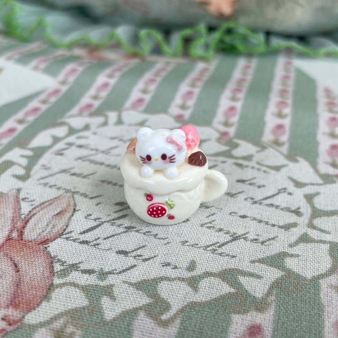 Handmade plush cat toy in a dessert cup with strawberry decoration, part of the Cuppa Kitties collection.