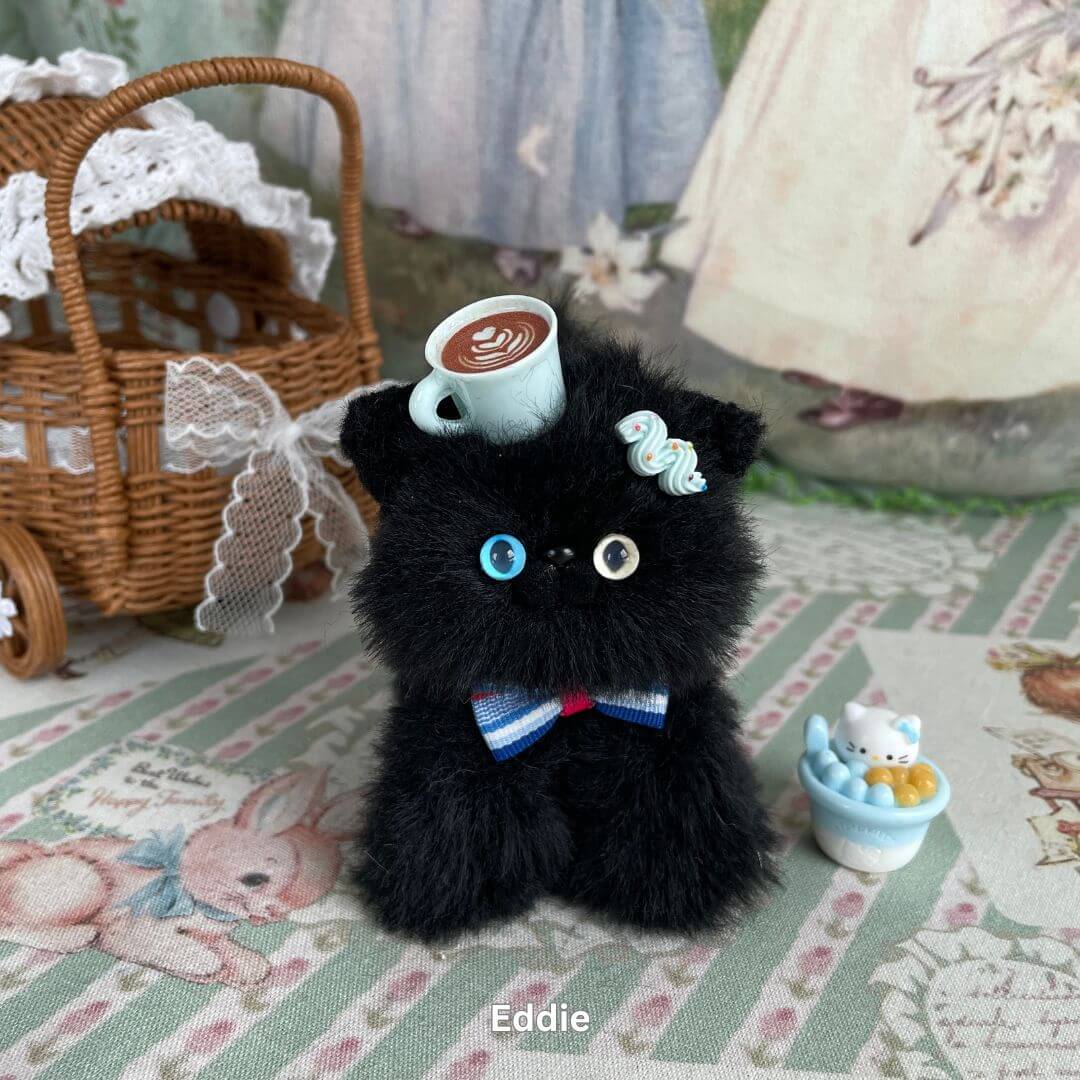 Handmade black kitten plush with mismatched eyes, coffee cup accessory, and decorative bow, part of Black Kitten Collection.