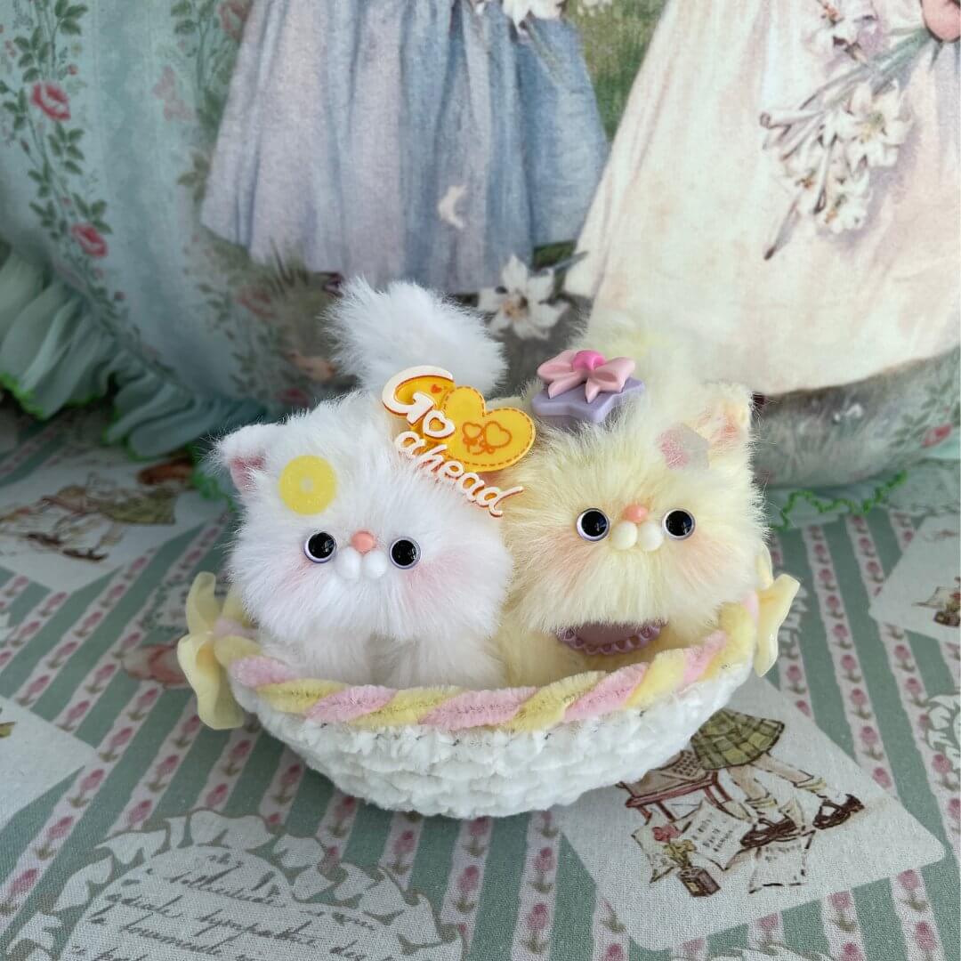 Two handmade whimsical plush kittens nestled in a charming cradle, perfect as miniature decorations or dollhouse accessories.