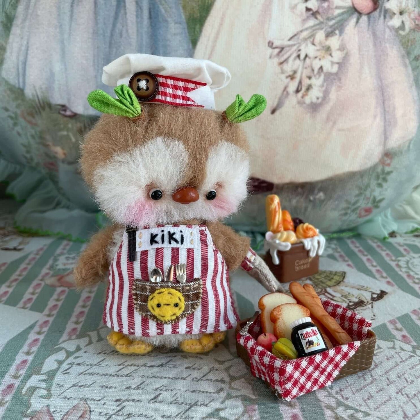 Handmade mini chef penguin plush with apron, hat, and food accessories on display, part of Kiki's Handmade Studio collection.