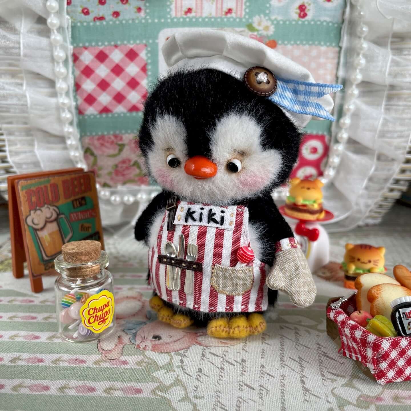 Cute mini chef penguin plush with hat and apron, wearing movable joints. Adorable handmade decoration from Kiki's Studio, 10 cm tall.