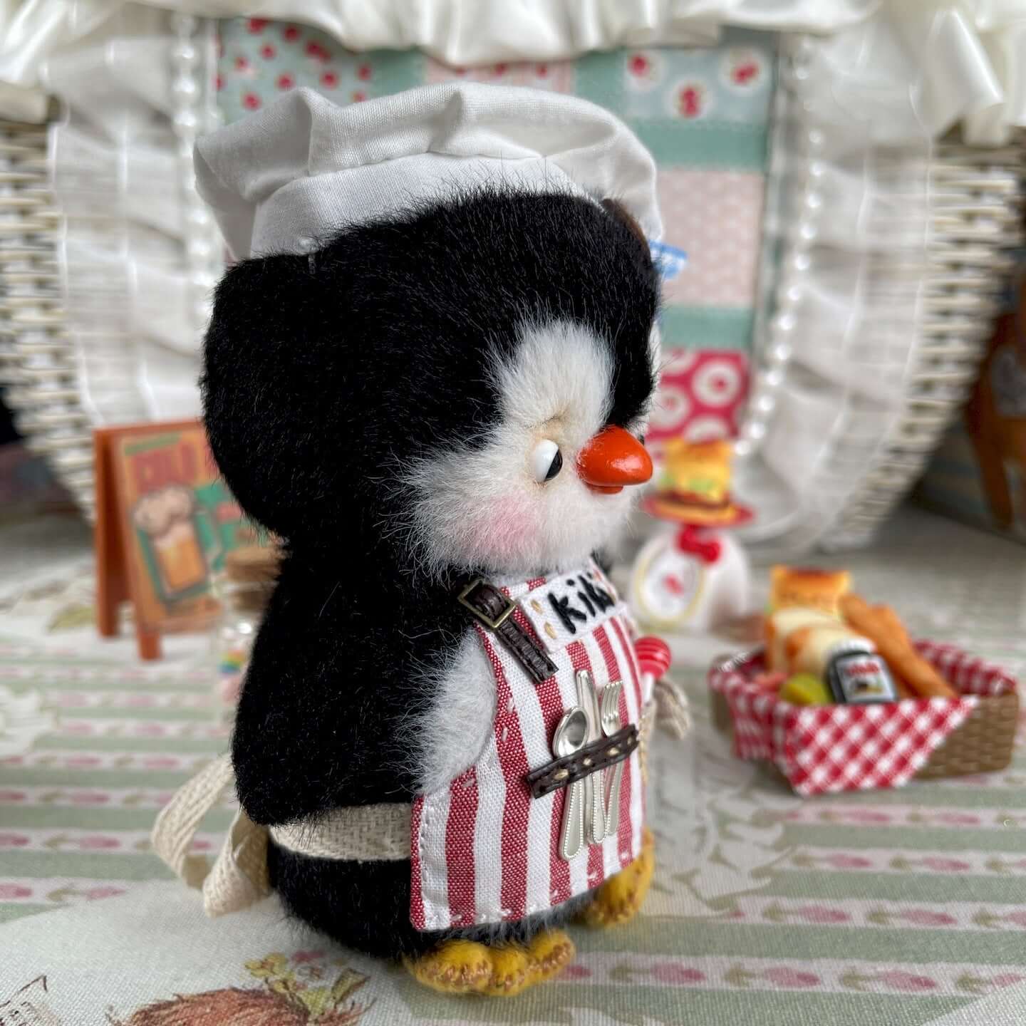 Mini Chef Penguin toy with apron and chef hat, featuring movable joints, designed by René from Kiki's Handmade Studio.