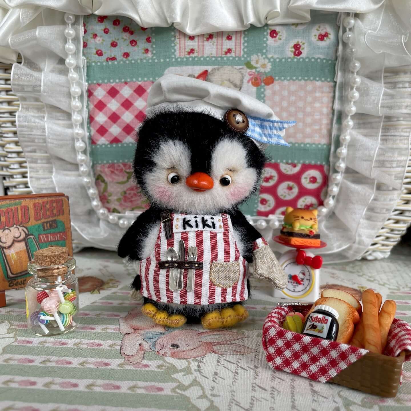 Mini chef penguin plush toy with custom apron, movable joints, and cooking accessories, set in a cozy kitchen scene.