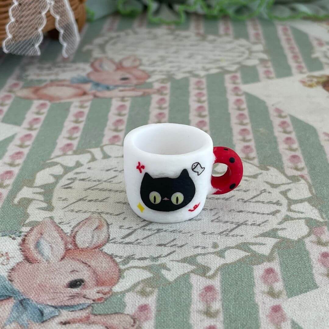 Miniature black kitty cup with playful design, perfect for dollhouse displays, collectible decor, or gifts for cat lovers.