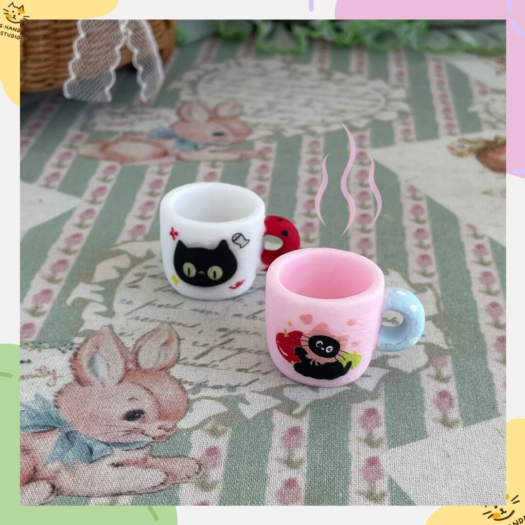 Miniature black kitty cups on decorative animal-themed tablecloth, perfect for dollhouse decor, desk displays, or cat lovers' gifts.