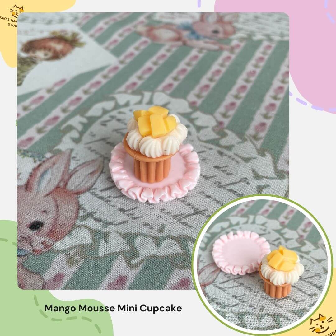 Miniature mango mousse cupcake on patterned tablecloth, ideal for dollhouse decor or cat-themed collections.