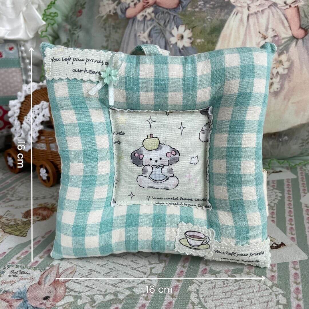 Cute checkered pillow with playful illustrations, featuring a whimsical animal print and tea-themed accents, ideal for cozy decor.