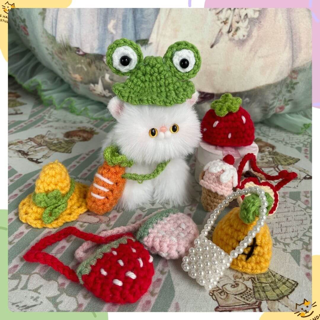 Handmade plush toy kitten with frog hat and cute accessories from Snuggle Bits, including pearl bag and fruit-themed purses.