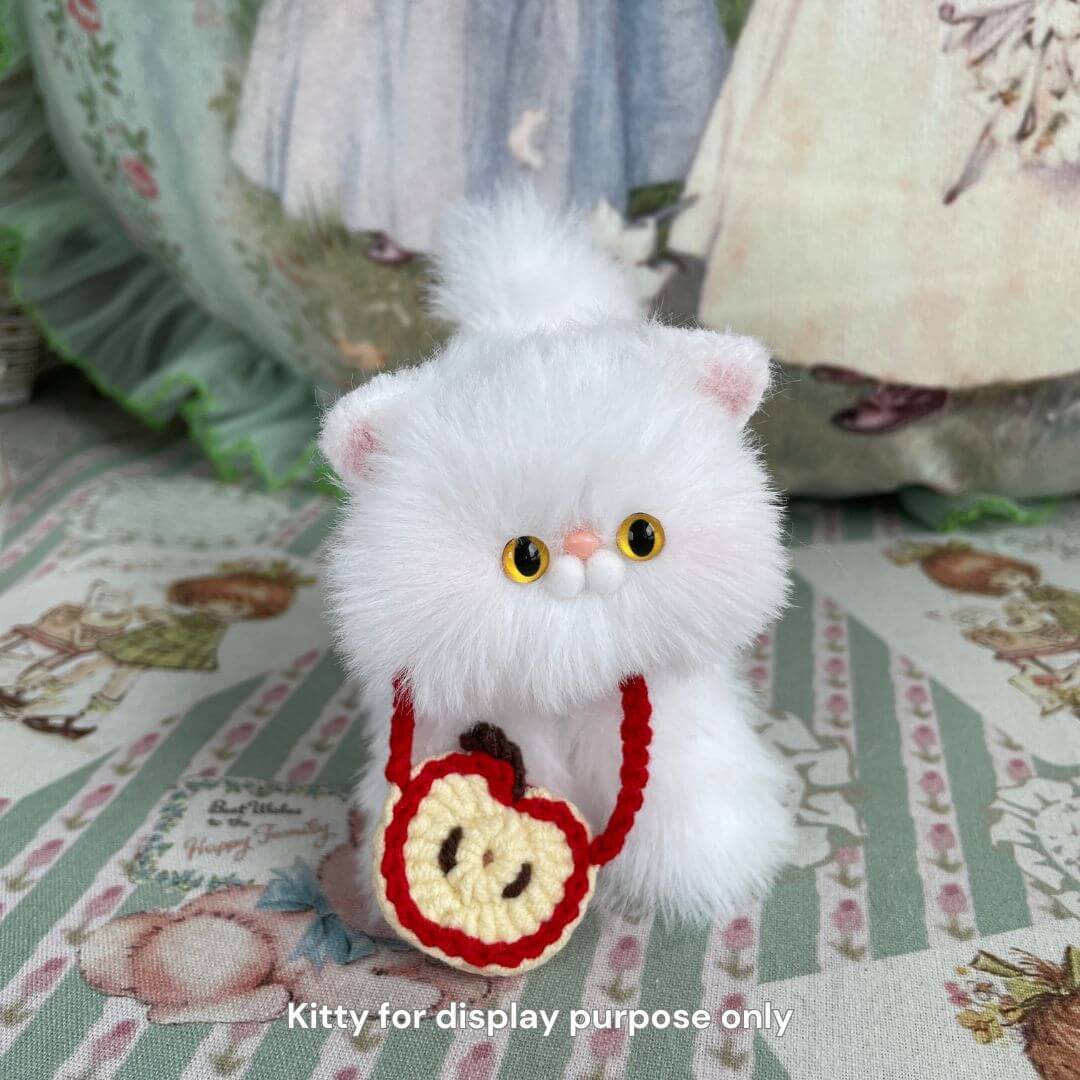 Handmade plush kitten with apple-themed bag, perfect for decorating or accessorizing, part of the Snuggle Bits collection.