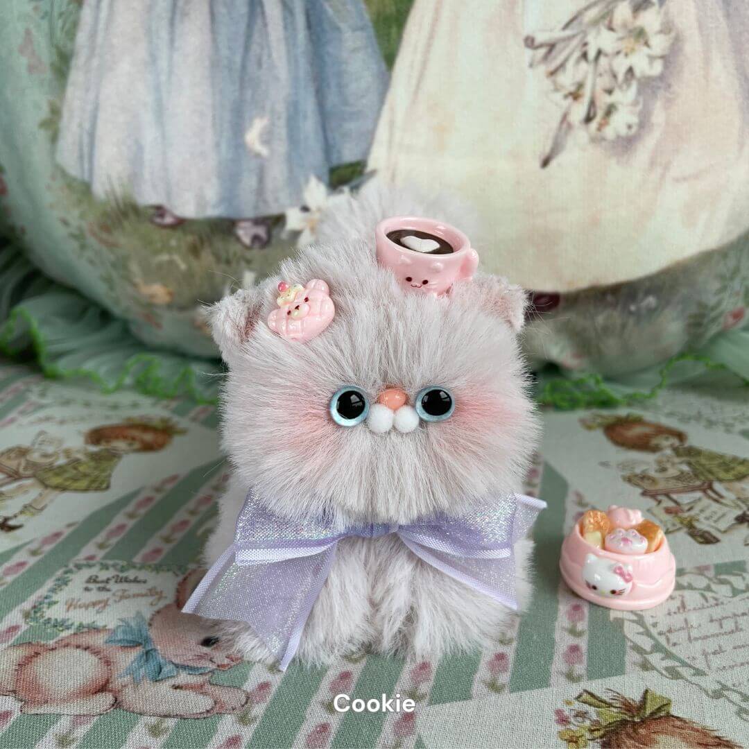Fluffy kitten plush toy with bow and teacup accessory, featuring soft faux fur and hand-sculpted core, part of the Fluffy Kitten Collection.