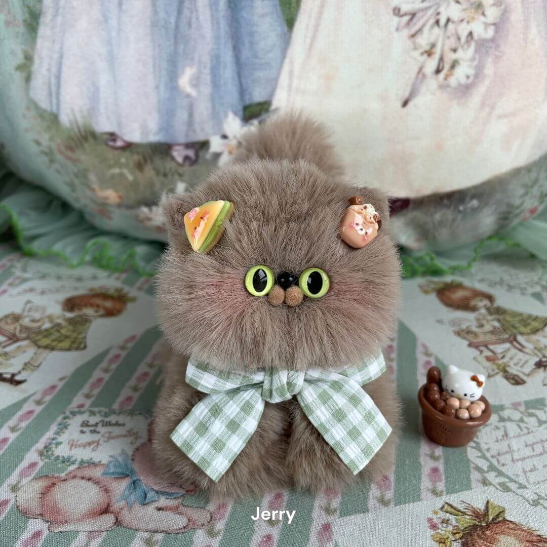 Fluffy faux fur kitten toy with green eyes, a checkered bow, and colorful ear decorations, part of handmade plush collection.
