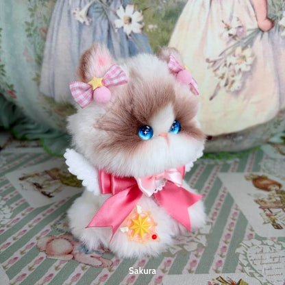 Handmade kitten from the Enchanted Big Paws Collection, fluffy with blue eyes, pink bows, and a cute pink ribbon.