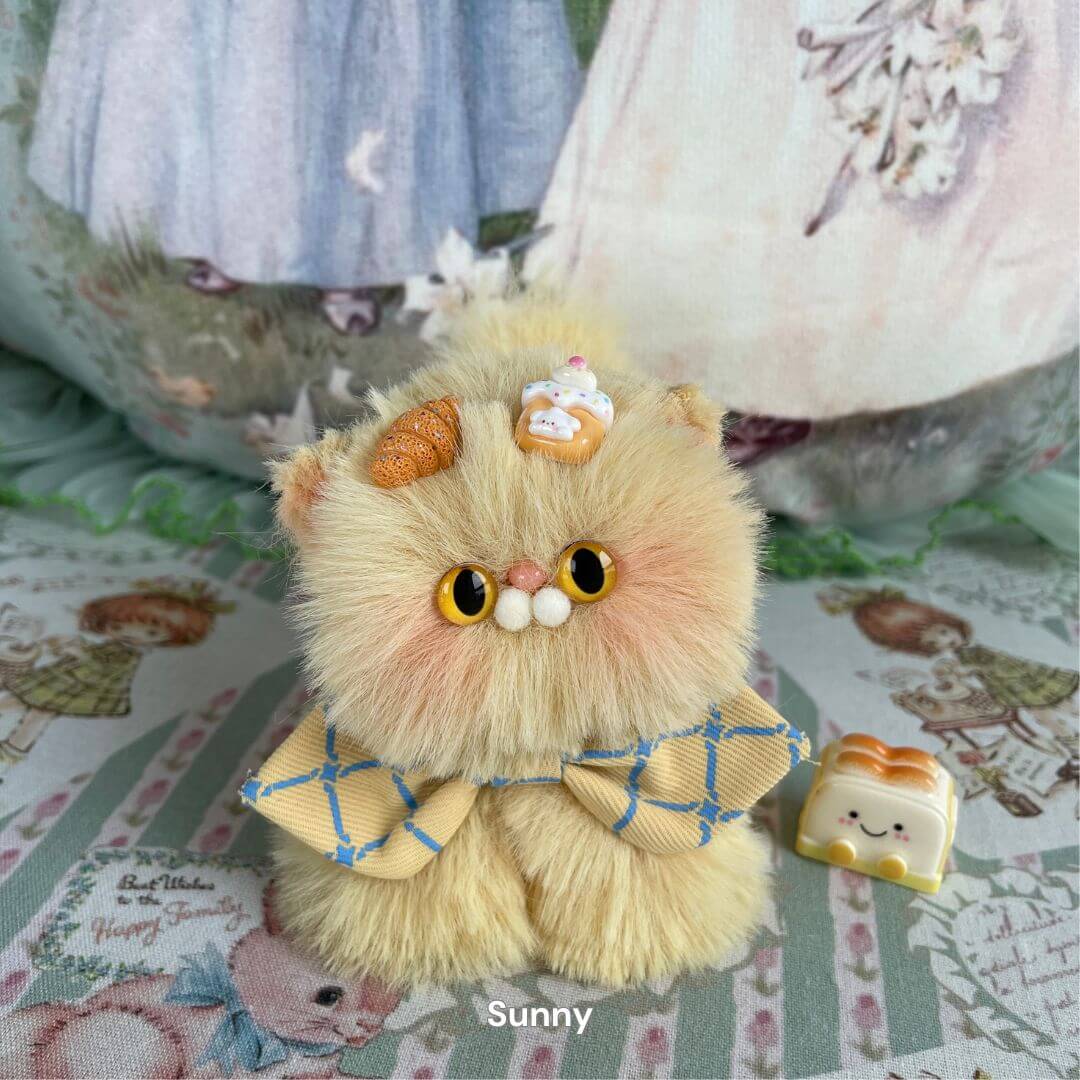 Fluffy handmade plush kitten with caramel fur, adorned with cupcake and bow, part of the Fluffy Kitten Collection. Name: Sunny.