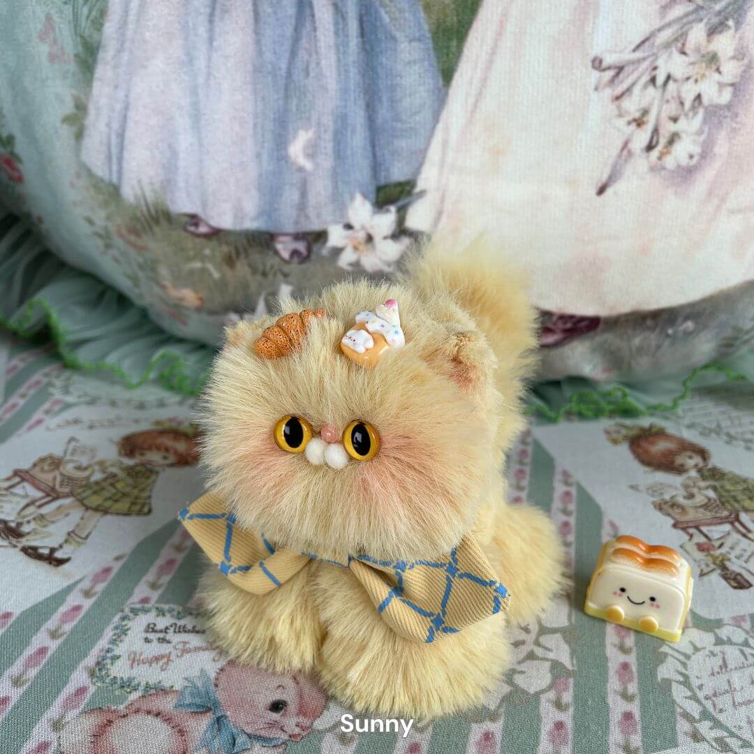 Handmade fluffy plush kitten toy with caramel tones, adorned with a bow and decorative sweets, from the Fluffy Kitten Collection.