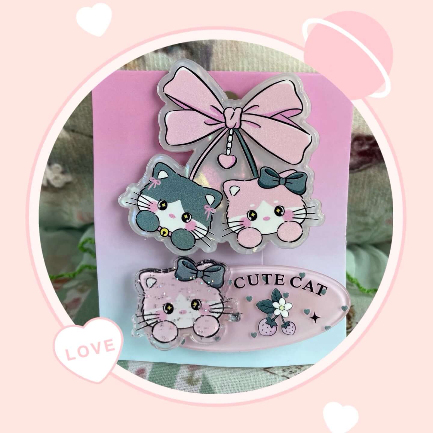 Pink and grey cat-themed hair clips with cute designs, featuring bows and playful kitten faces, perfect for hair or bags.