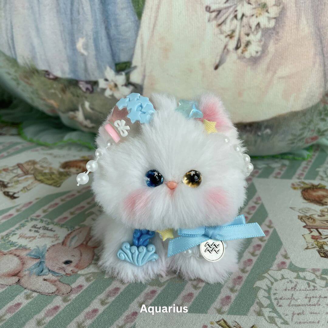 Plush Aquarius kitten with mixed-color eyes, adorned with charms and bows, part of the handmade Zodiac Kitten Collection.