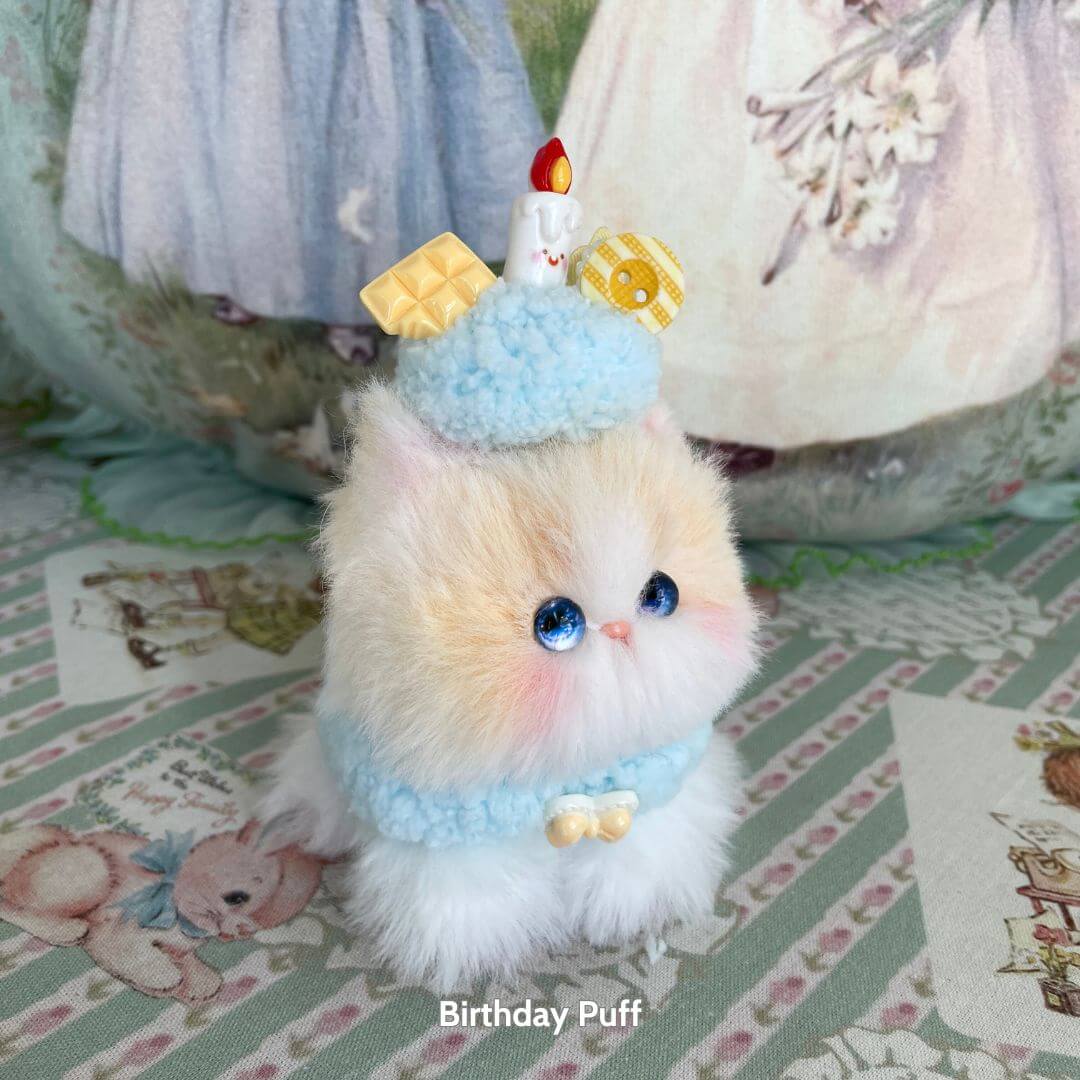 Mewlicious Collection handmade kitten wearing a blue dessert hat with a candle and sweet decorations, fluffy and cute collectible.