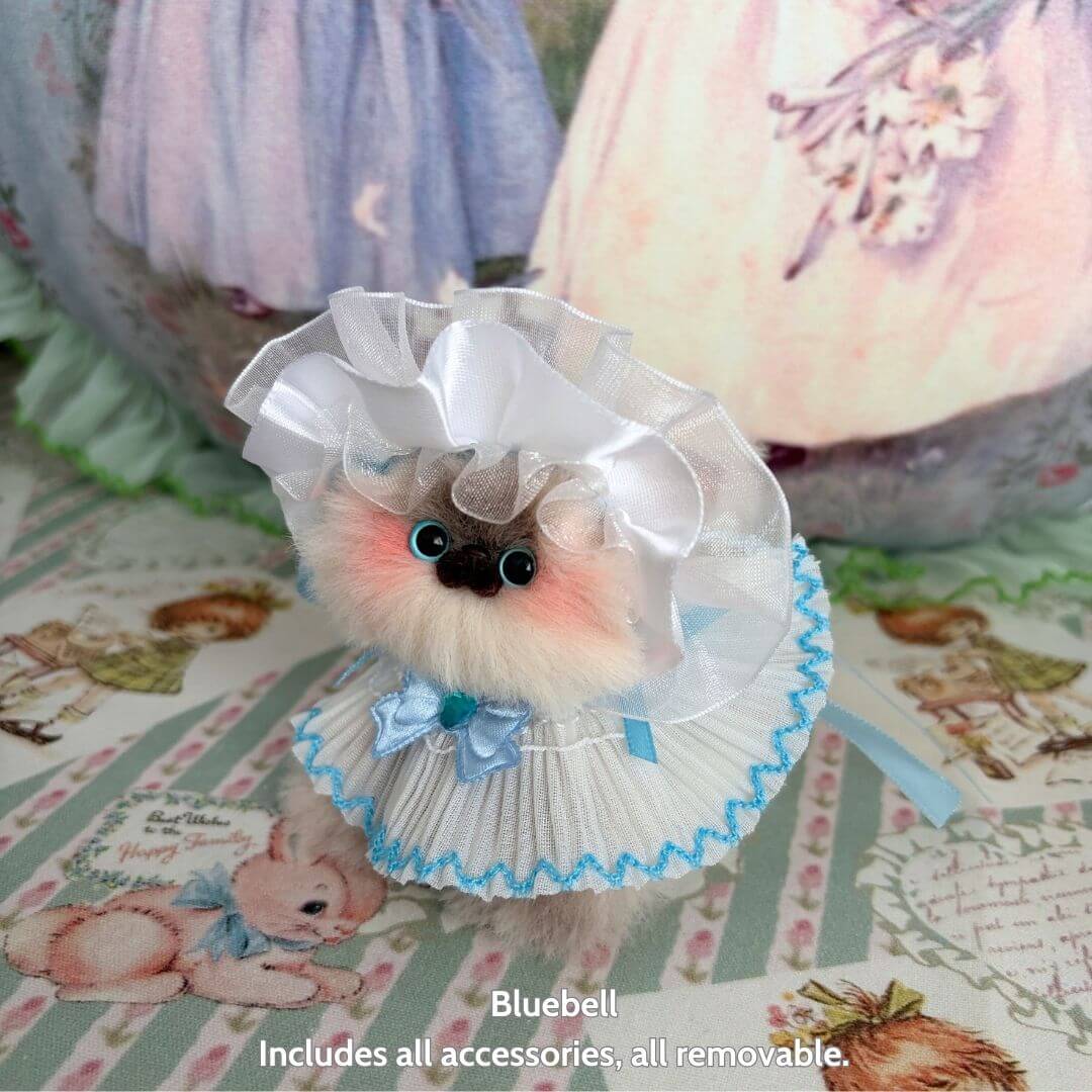 Handmade kitten Bluebell from Petals & Whispers Collection, dressed in a ruffled dress and bonnet with pastel colors and cute details.