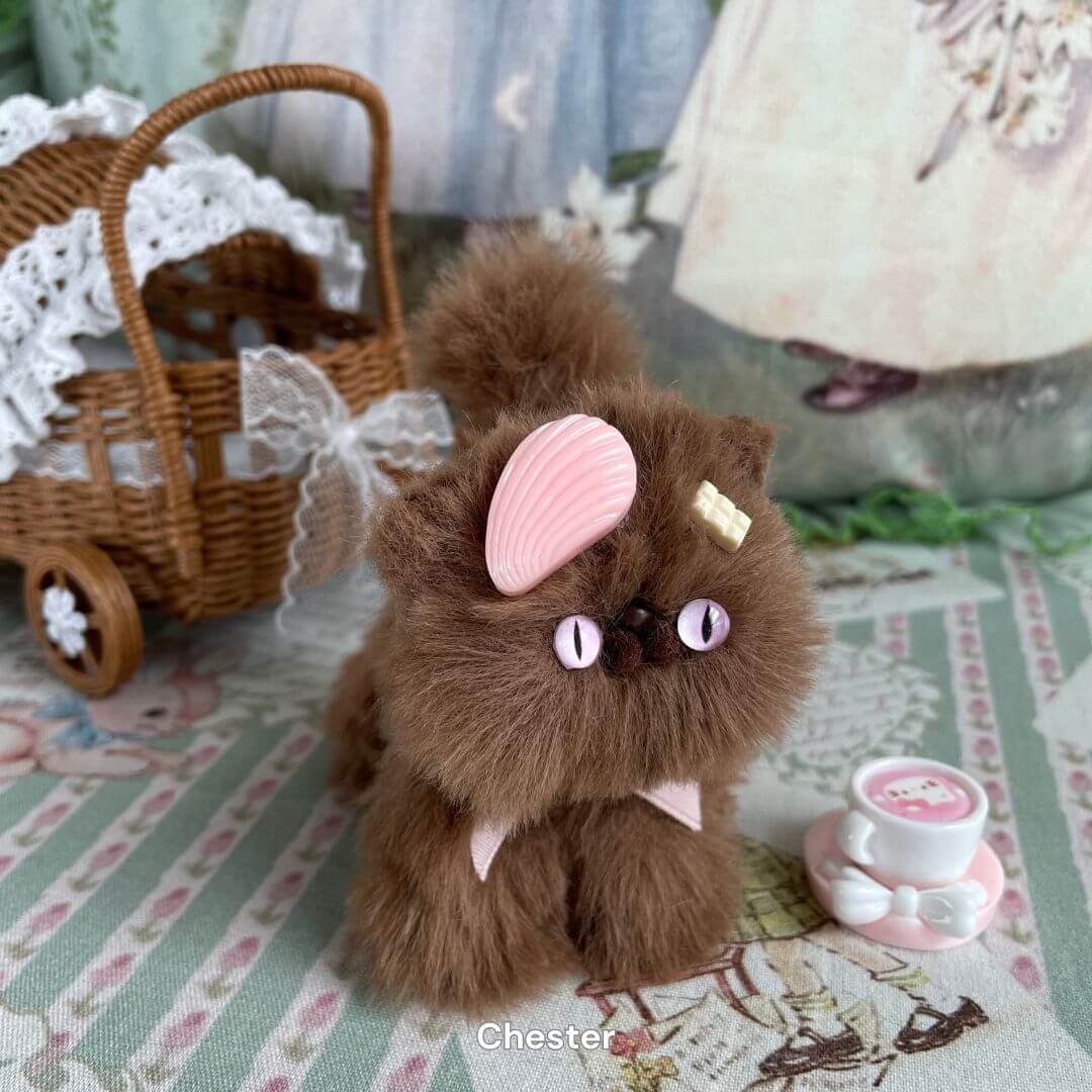 Handmade brown kitten plush toy with pink dessert accessory next to miniature teacup, part of the Brown Kitten Collection.