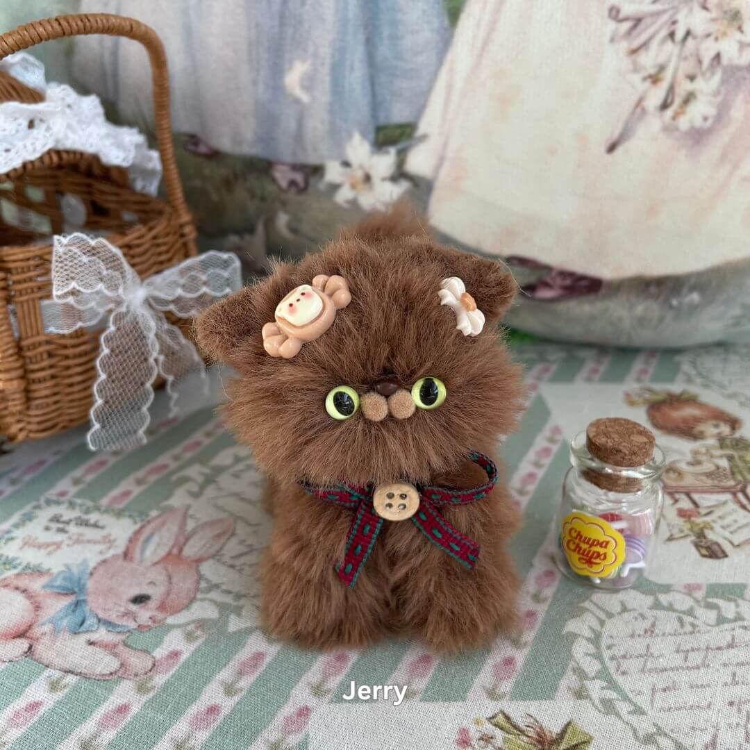 Handmade brown plush kitten toy with dessert-themed accessories on vintage background