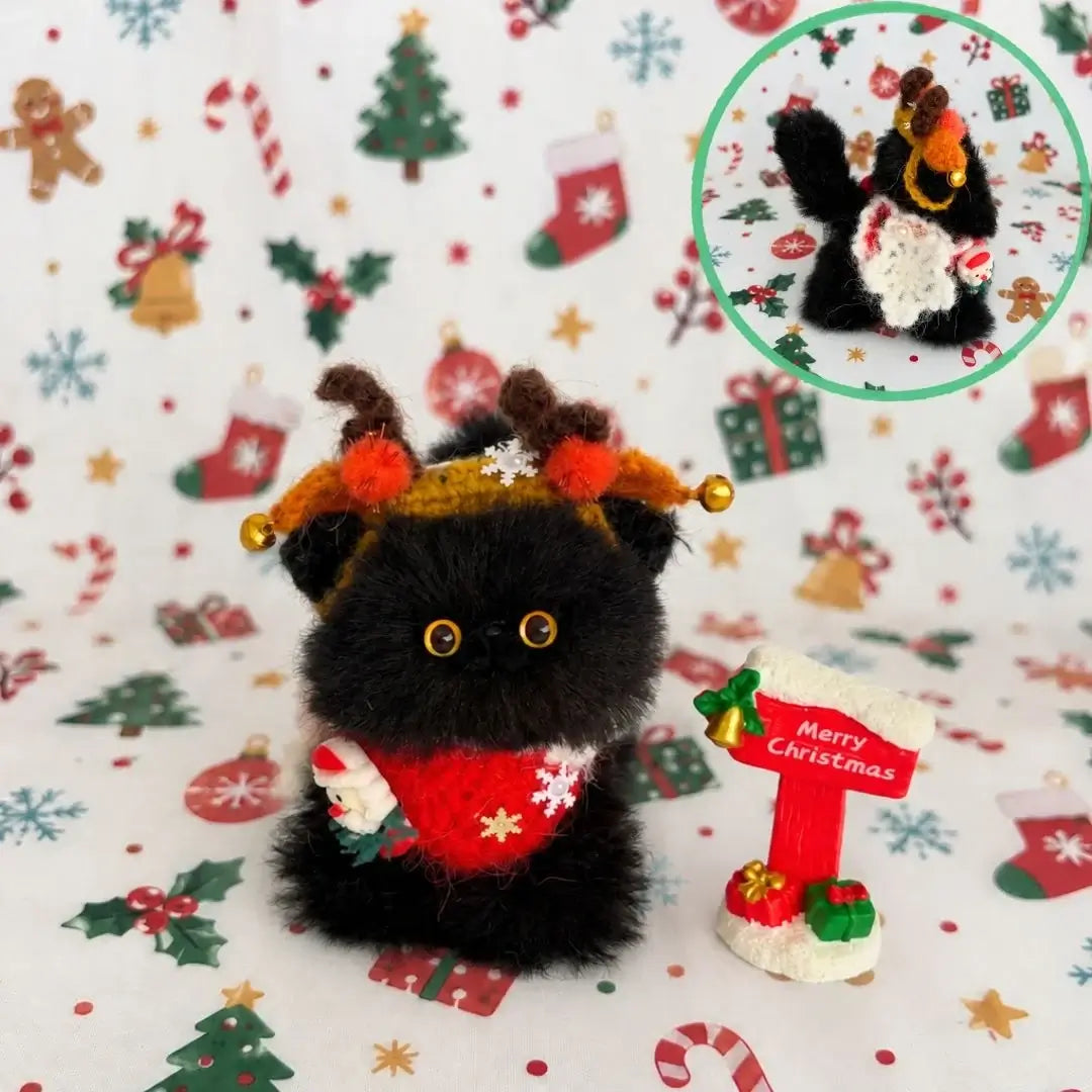 Black kitten wearing reindeer antlers and a red scarf.