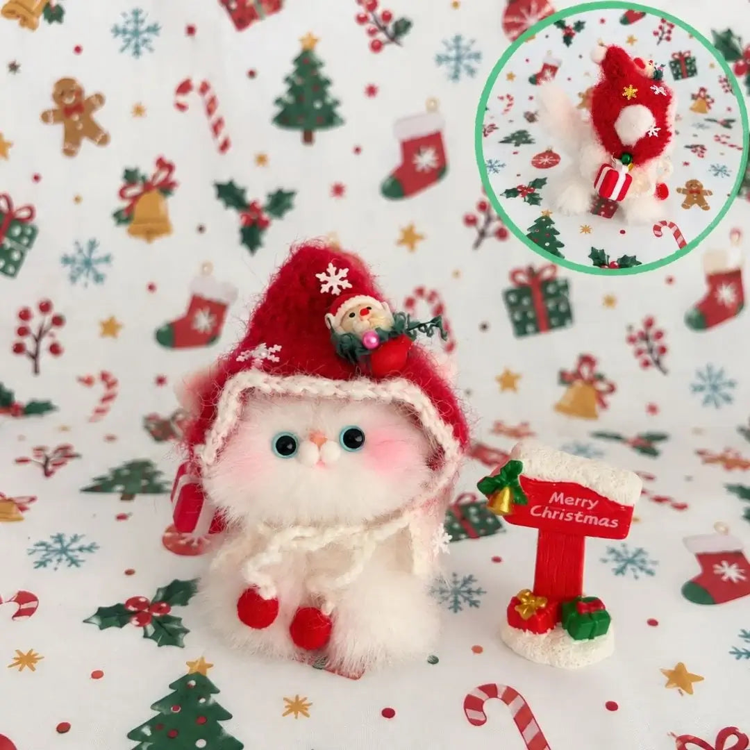 White kitten with blue eyes wearing a red Christmas hood.