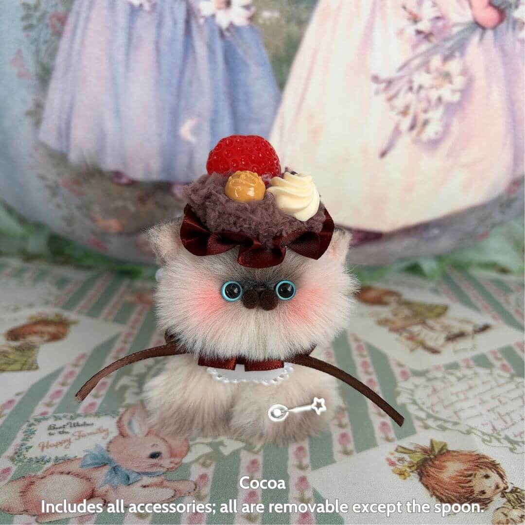 Sweet Treat Kitties handmade kitten with fluffy fur, pastel colors, and dessert-themed accessories including a cupcake and strawberry.