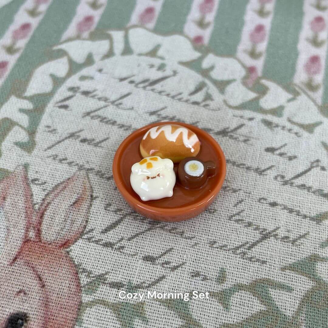 Miniature cozy morning set featuring a cute bear donut, coffee, and bread on a decorative background.