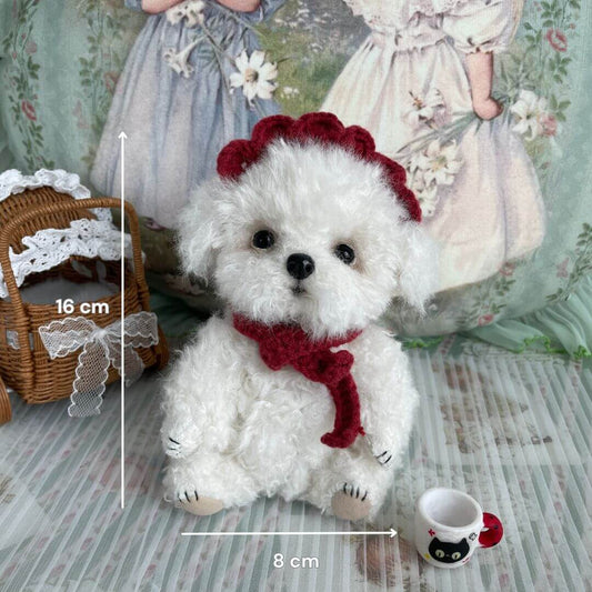 Cuddly curly teddy dog plush with red scarf, handmade by Anna from Kiki's Handmade Studio, sitting with accessories and crochet details.