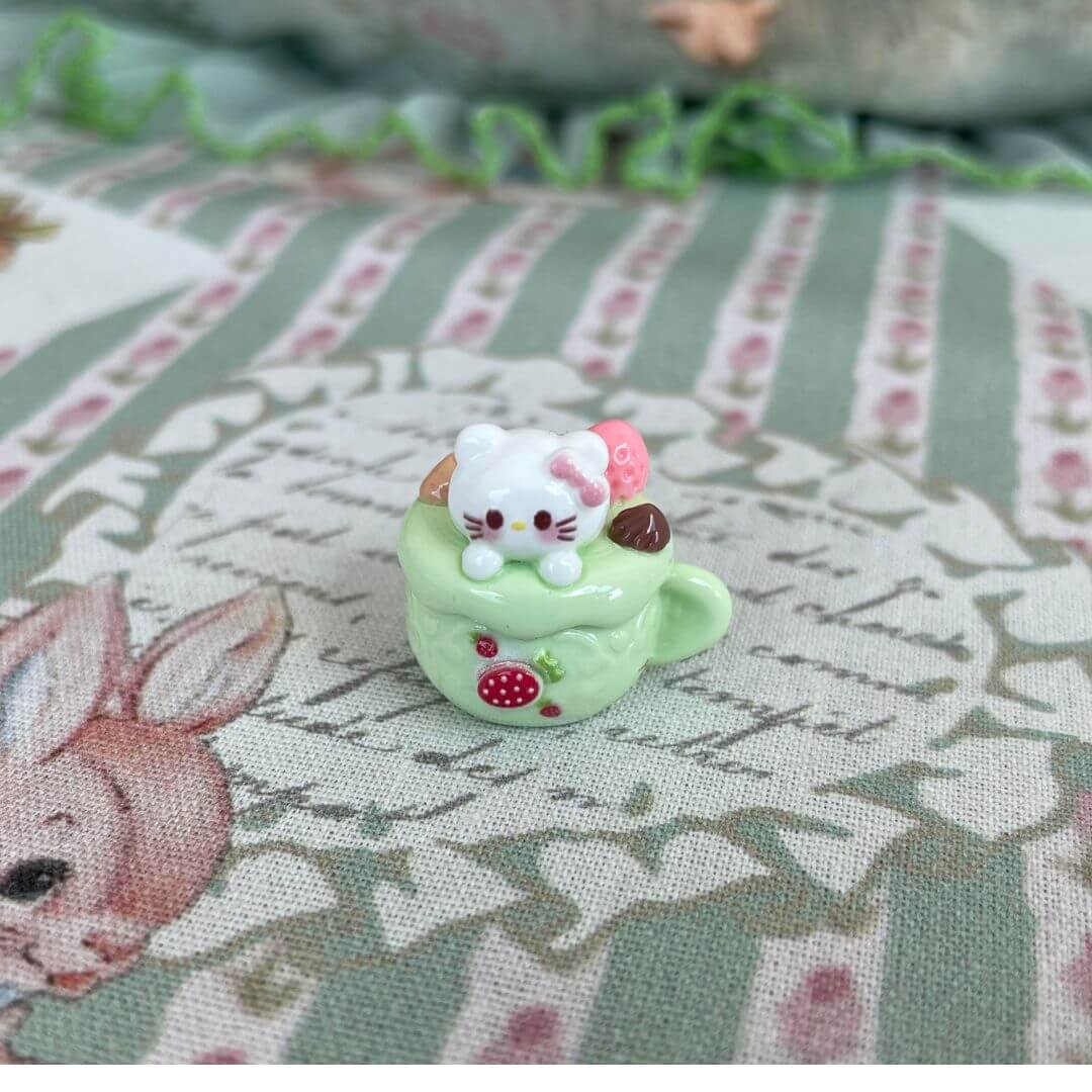 Plush kitty toy in a dessert cup; cute decoration with strawberry details on a patterned cloth; part of Cuppa Kitties collection.