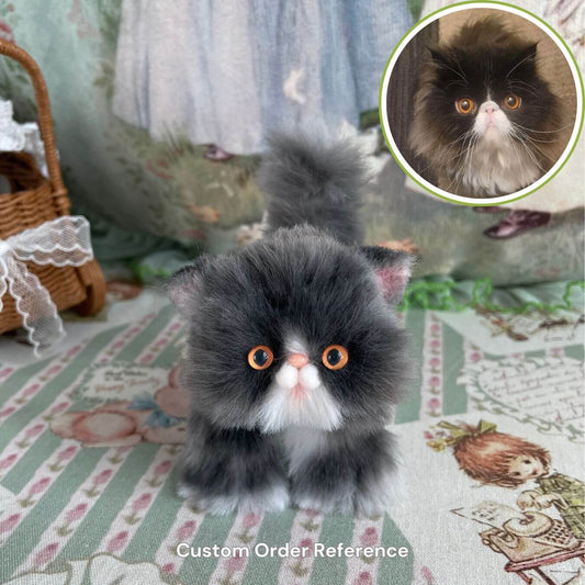 Handmade fluffy kitten plush toy resembling a real cat, featuring detailed fur and bright eyes, displayed on a decorative tablecloth.