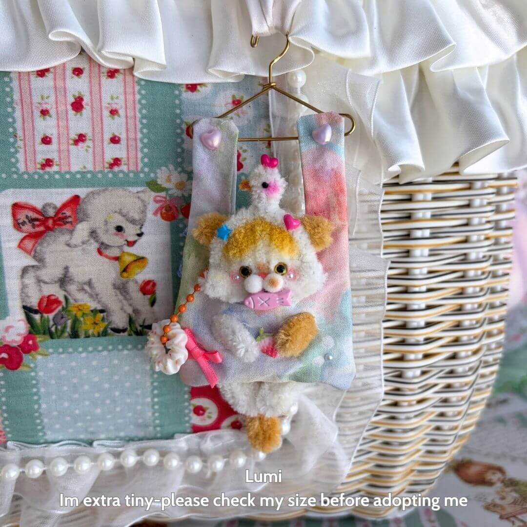 Alt Tag: Handmade kitten figurine in pastel colors, gently hanging from a miniature hanger, part of Little Hanger Pals collection.