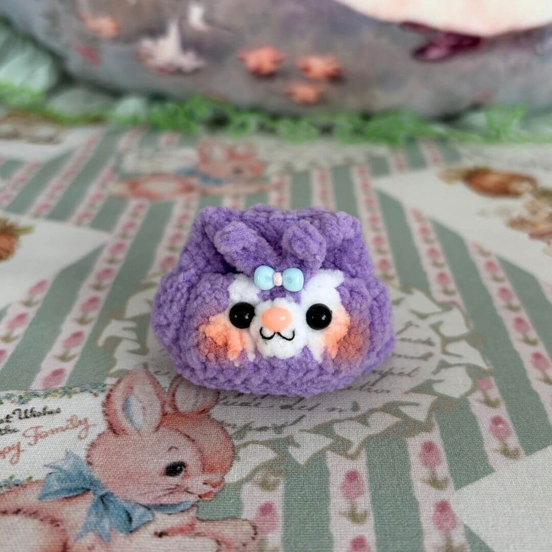 Cute kawaii cat figurine featuring a fluffy kitten in a purple color with a blue bow, showcasing the Handmade Mini Backpack design.