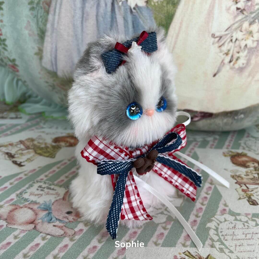 Handmade plush kitten decoration from Enchanted Big Paws Collection, wearing red and blue bow, unique gift for cat lovers.