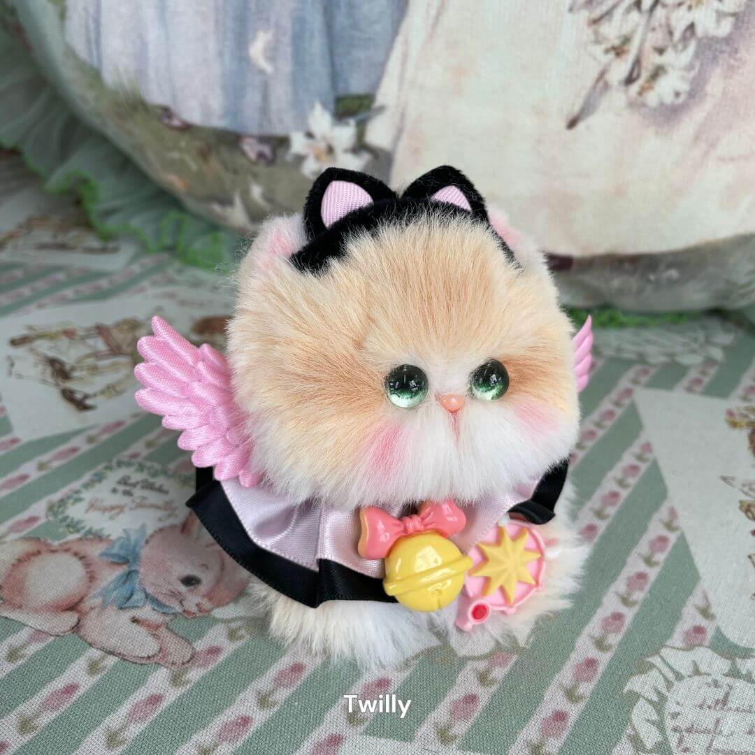 Handmade plush kitten from Fairy Paws Collection with pink wings, black ears, and star accessory on a floral background.