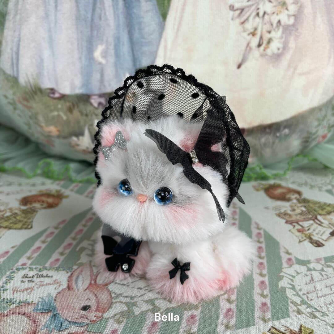 Fairy Paws Collection plush kitten with blue eyes, wearing a lace veil and bow, handmade with faux fur, set against a floral backdrop.